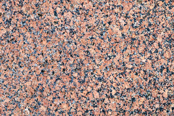 Polished red granite stone texture with black and white mineral specks. High-resolution natural...