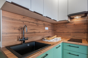 Bright and modern kitchen features a sleek black sink and wooden countertops. Freshly baked bread sits invitingly on a decorative plate, enhancing the cozy atmosphere.