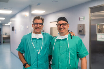 Two surgeons smiling and posing in hospital corridor