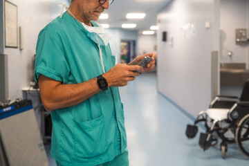 Surgeon checking smartphone in hospital hallway