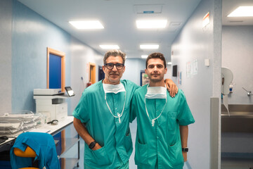 Two surgeons smiling and posing in hospital corridor