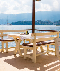 Outdoor cafe or restaurant with sea view and empty chairs. Coastal relaxation, summer tourism, and beachfront dining in the Mediterranean region.