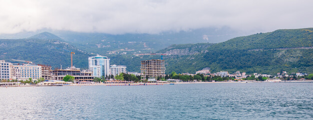 Banner coastal town skyline viewed from sea on cloudy summer day. Waterfront architecture, beach...