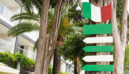 Empty green and white direction sign with Italian flag on tree, copy space. Travel guidance,...