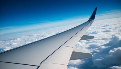 Fototapeta premium Airplane Wing Soaring Above Cloudscape Against a Clear Blue Sky Travel Concept