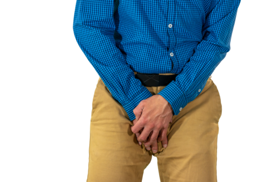 Man in casual attire shielding groin area with hands while standing in defensive position suggesting discomfort or vulnerability. Isolated