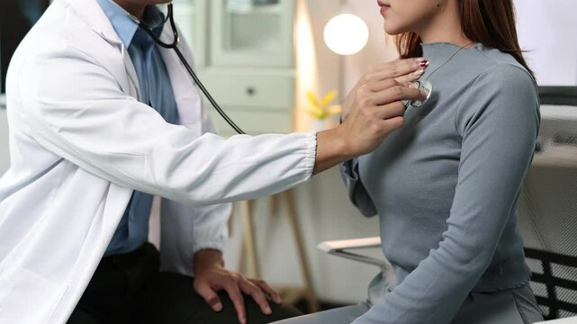 Doctor examining patient's chest with stethoscope in medical office.