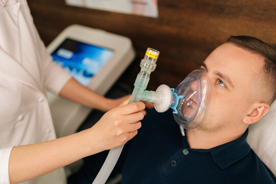 Cropped shot of skilled physician providing oxygen mask during respiratory therapy to male patient, enhancing breathing techniques and lung function. Training increases body adaptation abilities. - Powered by Adobe