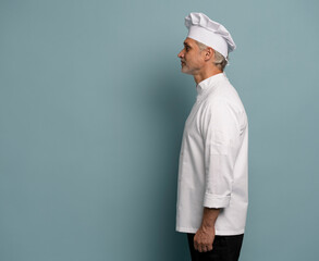 Profile side view half face portrait of handsome chef cook in beret and white outfit isolated on blue background