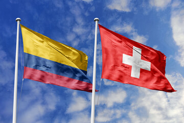 Waving flags of Colombia and Switzerland against a vibrant blue sky, symbolizing international...