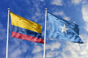 Waving flags of Colombia and Somalia against a vibrant blue sky, symbolizing international relations and friendship.