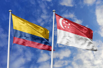 Waving flags of Colombia and Singapore against a vibrant blue sky, symbolizing international relations and friendship.