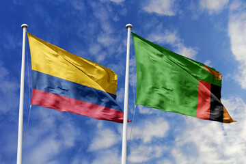 The Colorful National Flags of Colombia and Zambia Waving Resiliently Together Under a Bright Blue...
