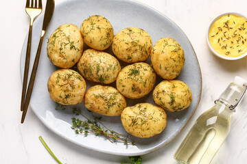 Plate of boiled baby potatoes with dill and sauce on white background