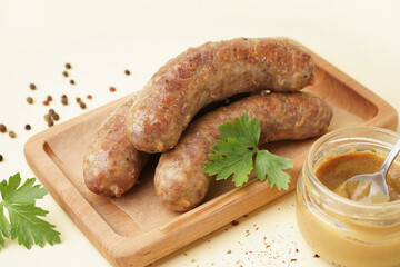 Wooden board of tasty homemade sausages with mustard on yellow background