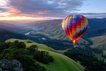 Fototapeta premium Colorful hot air balloon soaring over green hills at dawn in a scenic landscape
