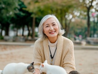 Senior woman with silver hair, smiling while interacting with playful cats in a serene outdoor park setting, showcasing a joyful connection with animals and nature