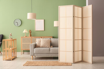 Modern living room interior with grey sofa, cabinet and folding screen