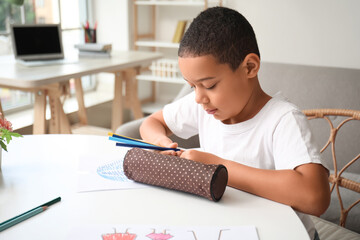 Little African-American boy with pencil case at home