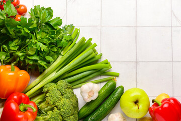 Fresh vegetables and fruits on white tile background