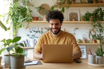 Young latin man working from home using laptop in cozy green workspace