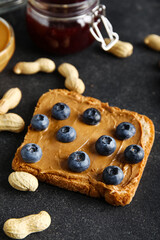Toast with peanut butter and blueberries on black background