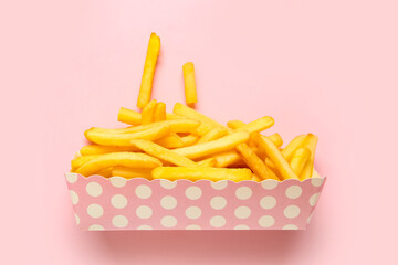 Paper box with tasty french fries on pink background