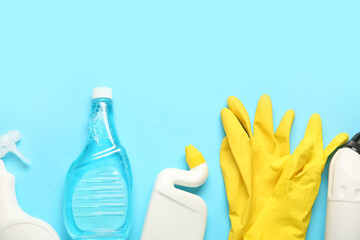 Bottles of detergent and gloves on blue background