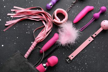 Shopping bag with different sex toys on grunge black background