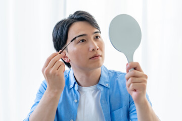 鏡を見ながら眉毛を描く男性