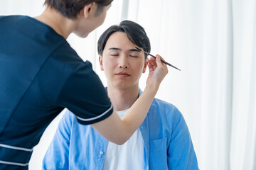 眉毛を描いてもらう男性