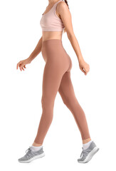 Sporty young woman in beige leggings on white background