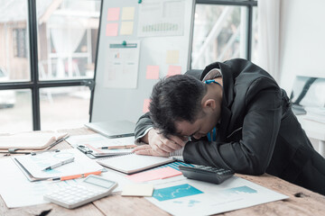 Exhausted office worker sleeping on desk with laptop on it. Lack of energy in office in the...