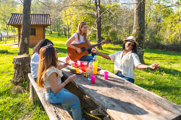 Group of diverse women having picnic and playing guitar in a park