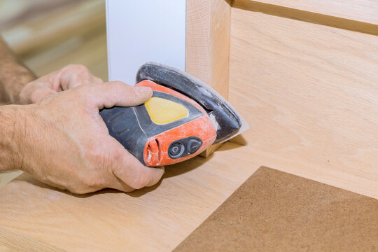 Skilled craftsman uses power sander on wooden surface to achieve smooth finish at wooden railings, stairs