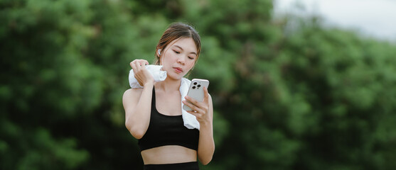 A fit and focused woman jogs outdoors in a serene green park, wearing activewear and earphones,...