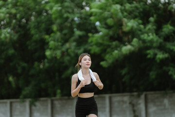 A fit and focused woman jogs outdoors in a serene green park, wearing activewear and earphones,...