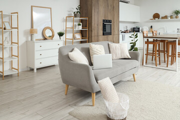 Interior of light kitchen with counters and laptop on sofa