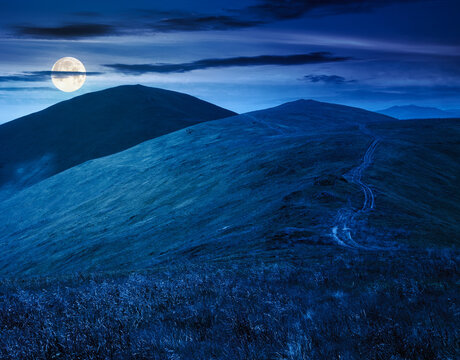 scenic mountain landscape with hill at night. travel background in summer. scenery of ridge with steep slope in full moon light. beautiful view of a terrain with grass on high altitude under dark sky
