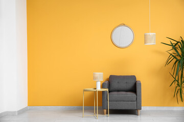 Armchair, coffee table with lamp and mirror on yellow wall in room