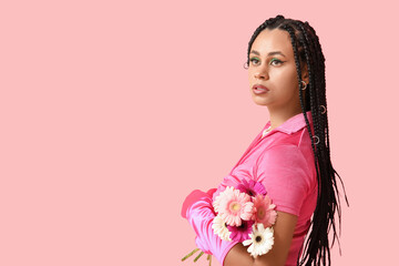 Stylish African-American woman with braids and flowers on pink background