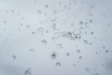 Raindrops and bubbles scatter across a wet surface, capturing nature’s freshness and moisture in...