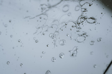 Raindrops and bubbles scatter across a wet surface, capturing nature’s freshness and moisture in...