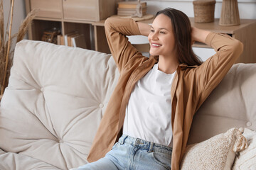 Young woman sitting on beige couch at home