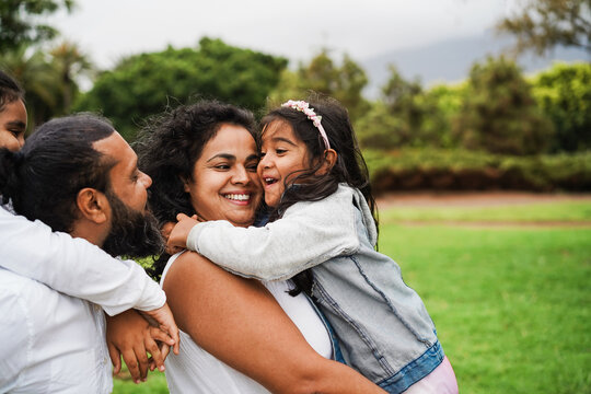 Happy indian family having fun playing with children outdoor at city park - Summer time, love and parenthood concept - Main focus on mother face