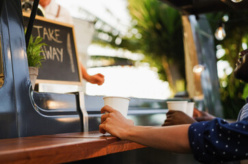 People are waiting outside of food truck while young chef preparing dinner - Summer meal and small business concept concept - Focus on girl hand