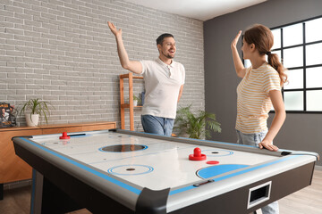 Obraz premium Young friends giving each other high-five near air hockey at home