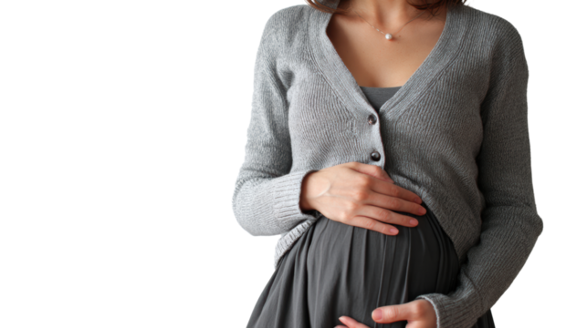 Pregnant woman in a cozy cardigan gently cradles her baby bump with a serene expression.