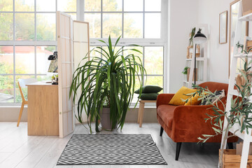 Interior of stylish living room with brown sofa, folding screen and comfortable workplace