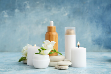 Composition with cosmetic products, spa stones, burning candles and flowers on color grunge background